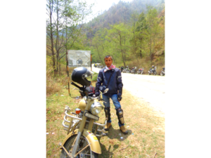 A rider standing with a Royal Enfield bike.