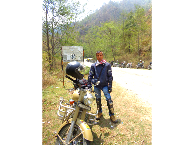 A rider standing with a Royal Enfield bike.