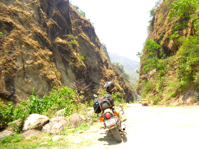 A bike as seen from rear end and a narrow passage between two mountains