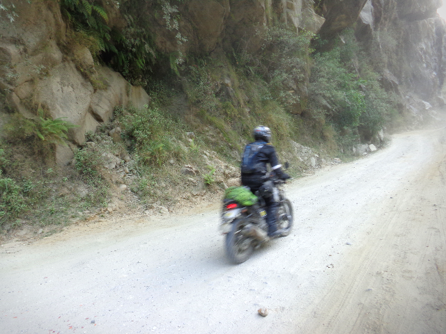 A rider is riding on a rugged terrain in a hilly road